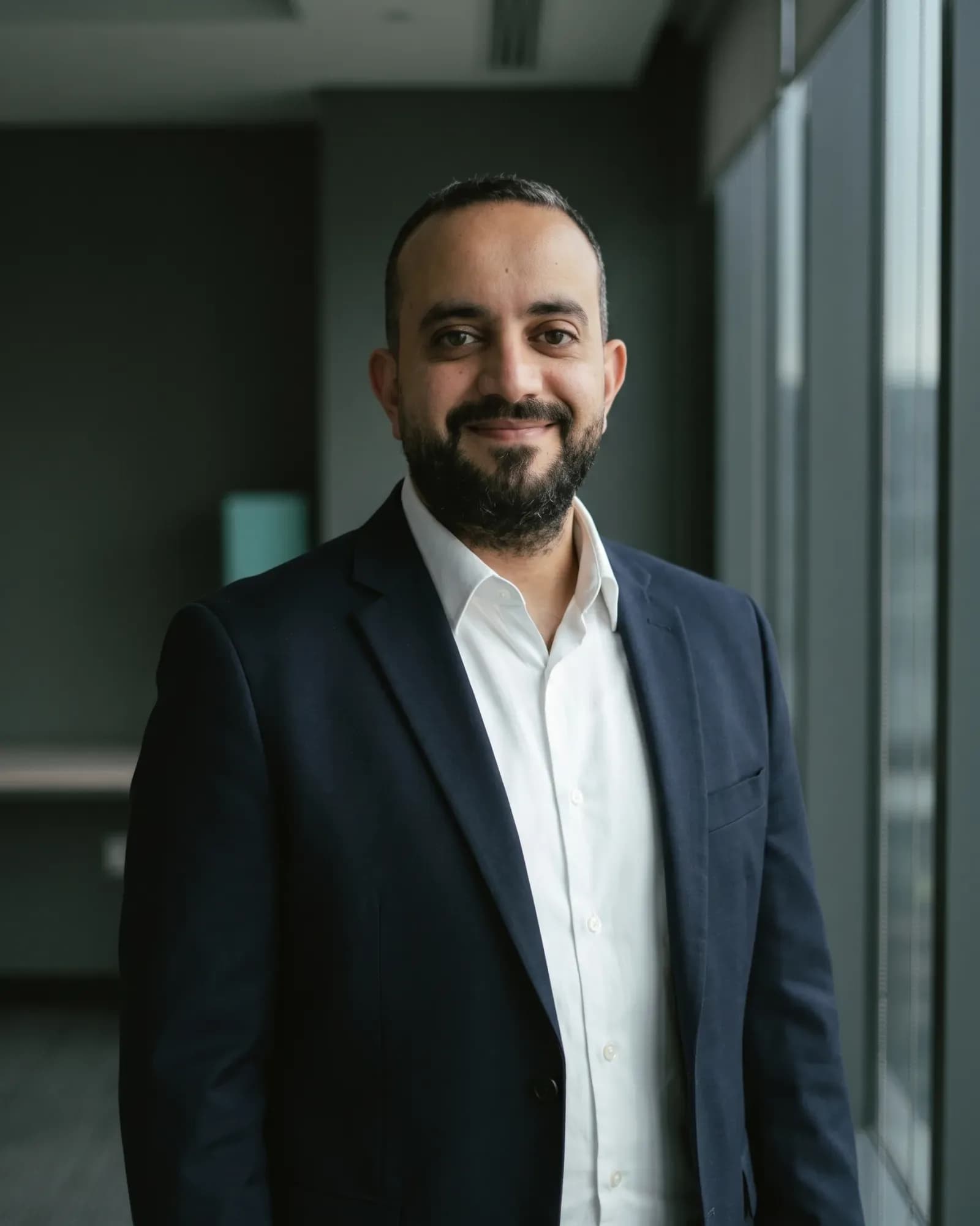 Ahmed Essam in a leadership portrait, wearing a navy suit and white shirt